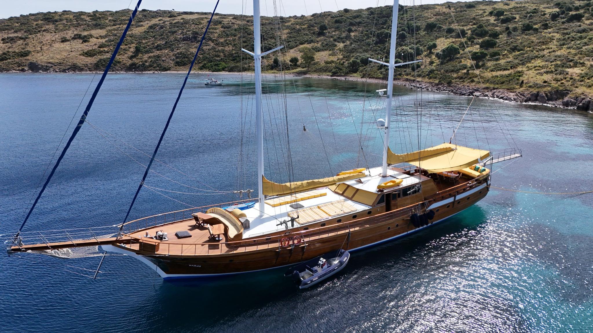 aerial view of traditional wooden gulet with white tender boat in turquoise Mediterranean bay