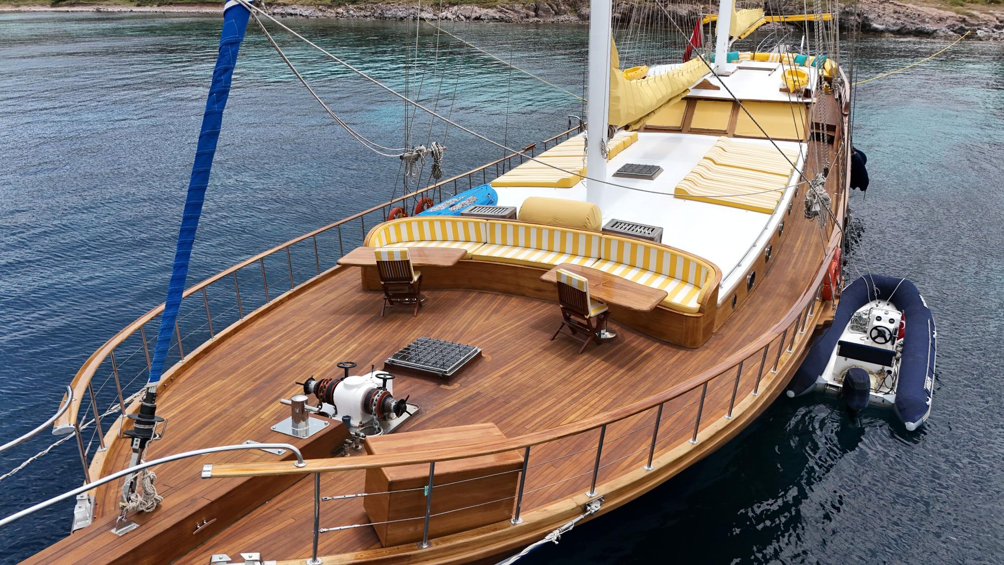 wooden gulet bow deck with curved yellow striped bench seating and teak planking