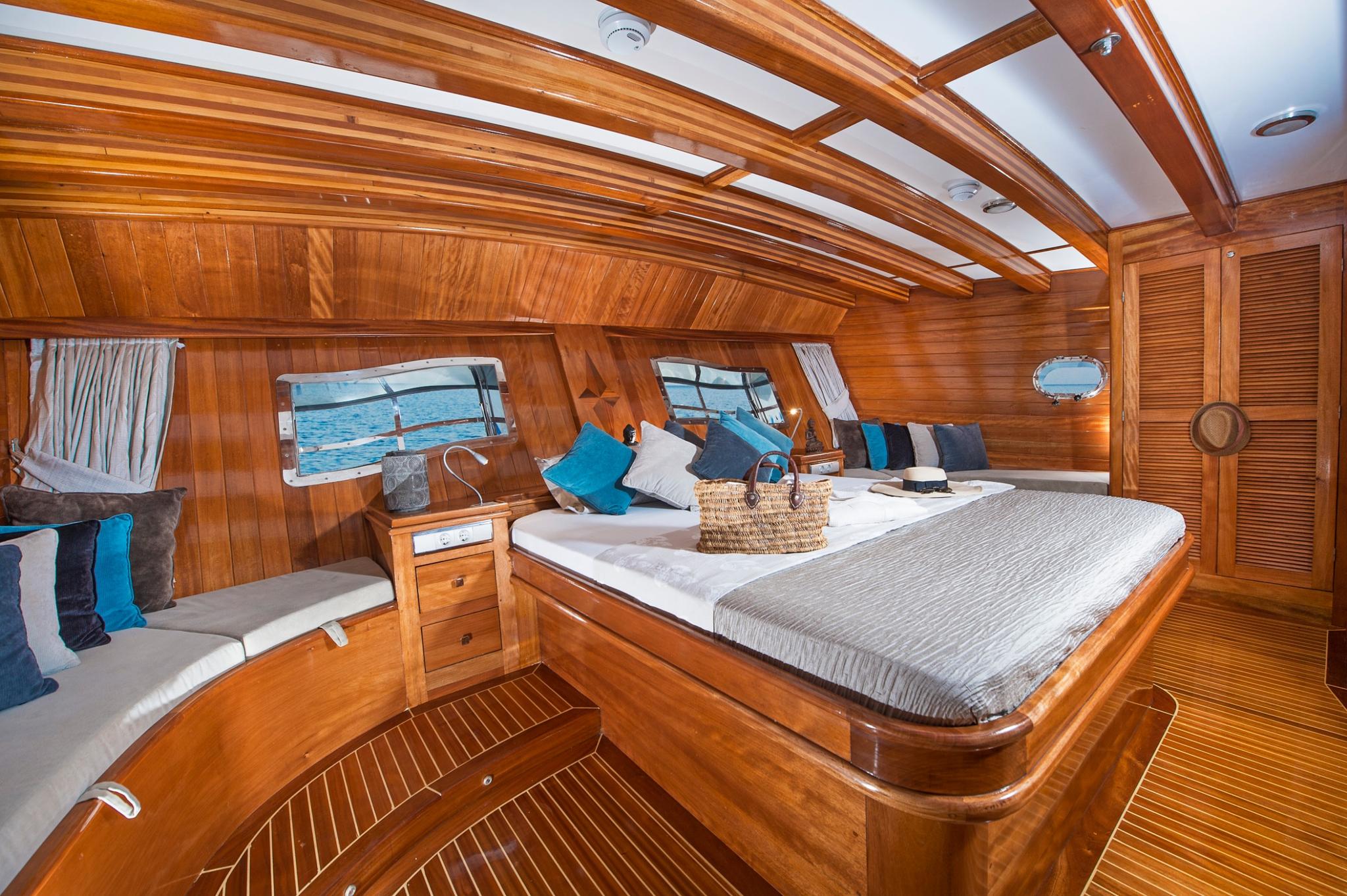 yacht guest cabin featuring double bed, single berth, wooden paneling and portholes