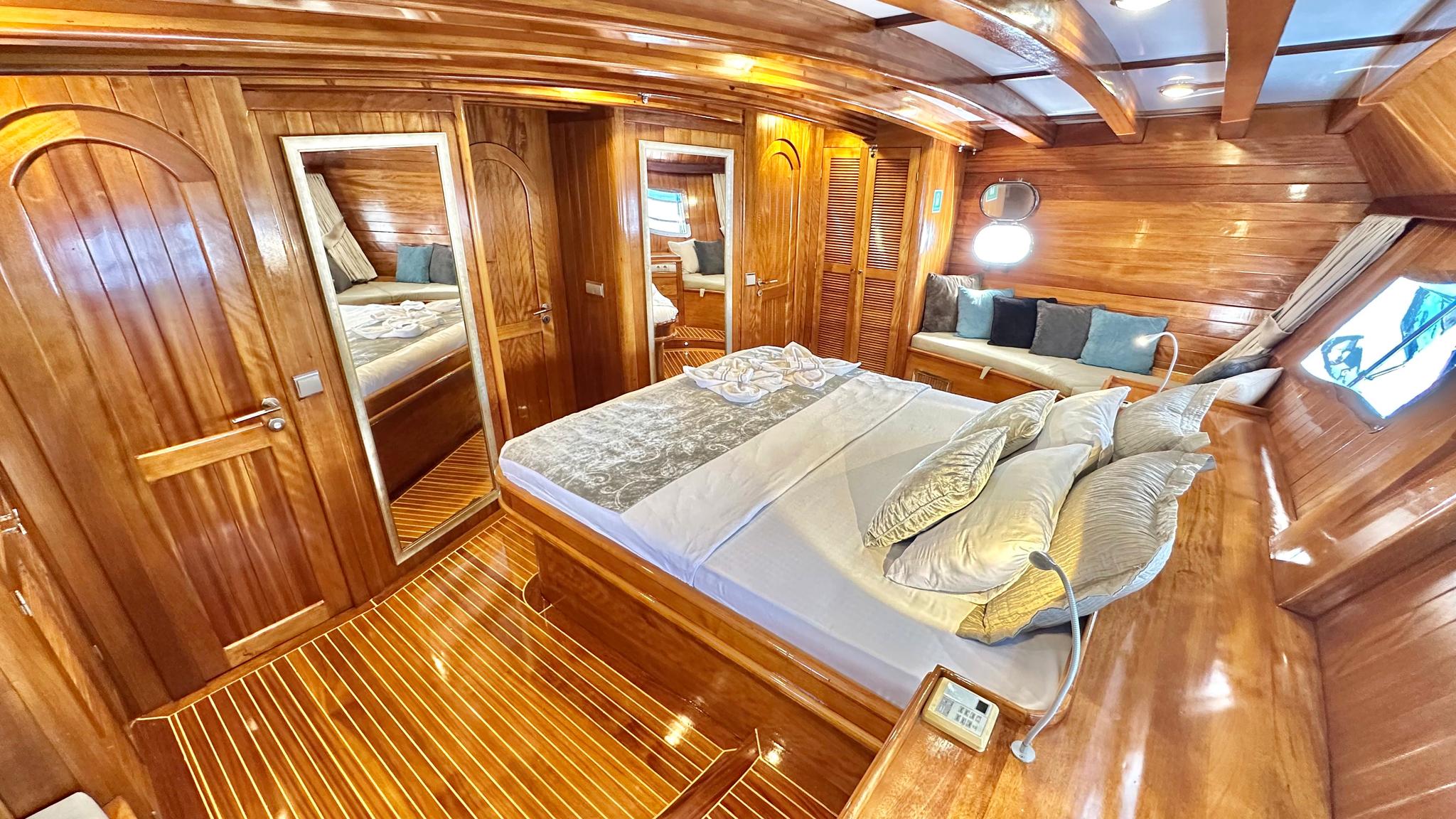 luxury yacht master cabin featuring double bed with beige bedding and built-in seating area