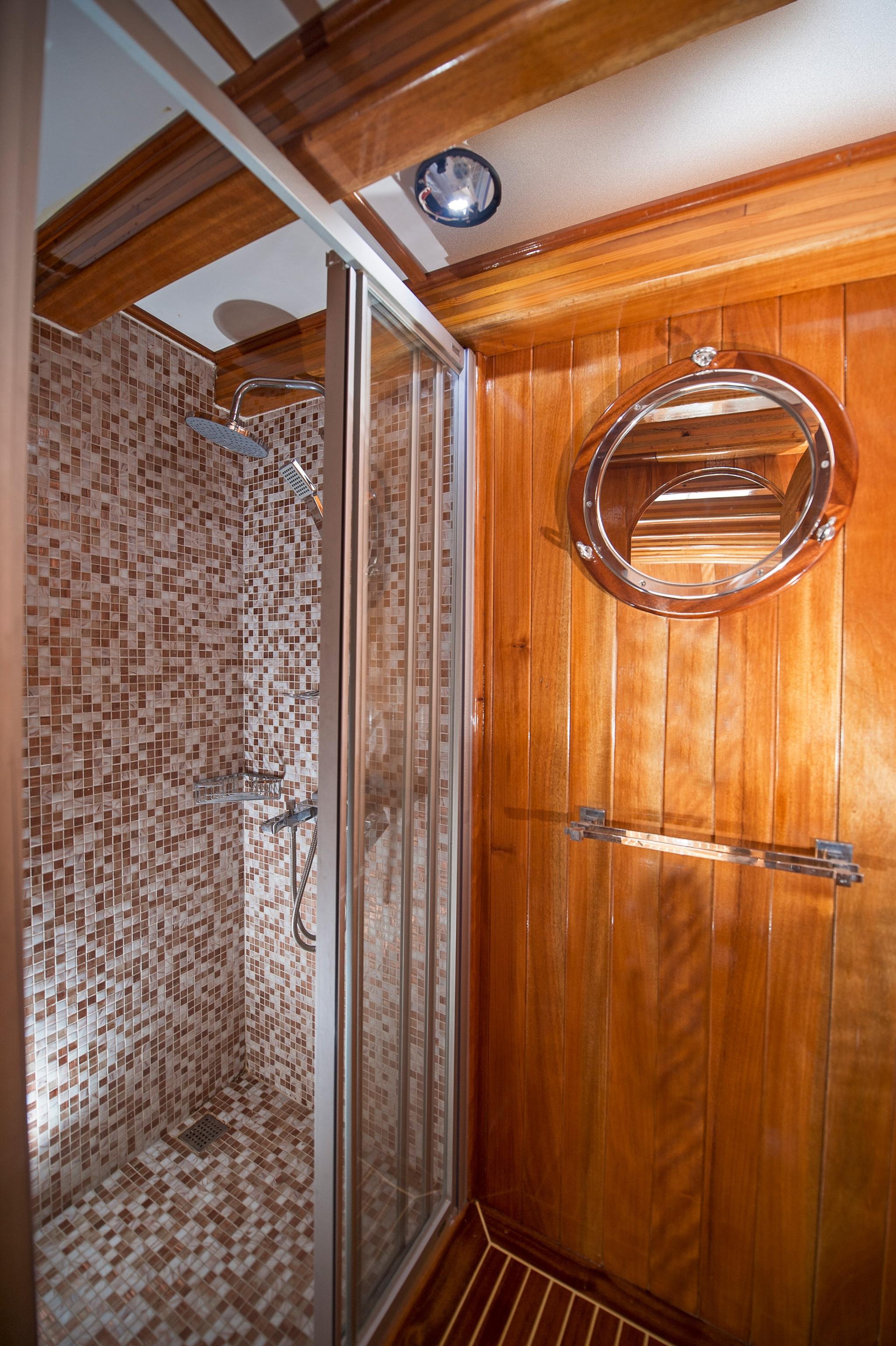 yacht bathroom featuring glass shower enclosure with mosaic tiles and circular porthole window