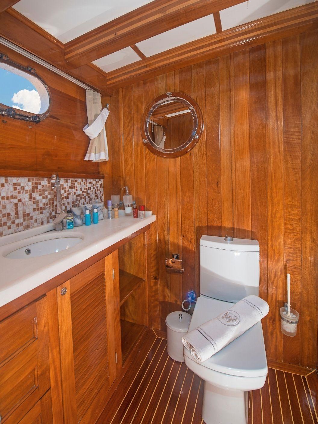 yacht bathroom with white toilet, sink vanity, mosaic tile backsplash and round porthole window