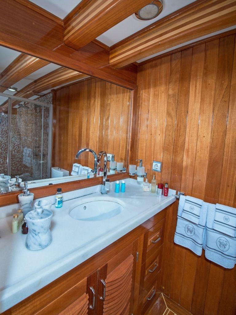 luxury yacht bathroom featuring teak wood paneling, marble vanity countertop, and chrome fixtures