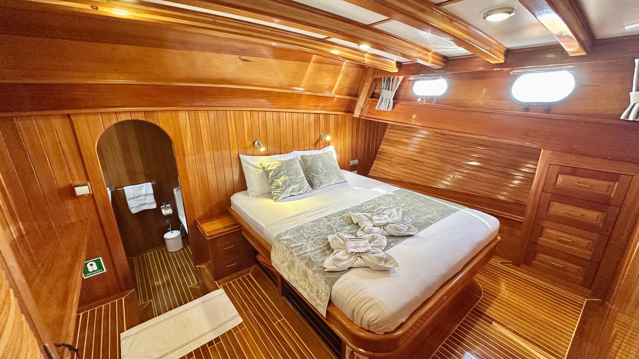 yacht guest cabin featuring double bed with patterned bedding and arched en-suite bathroom entrance