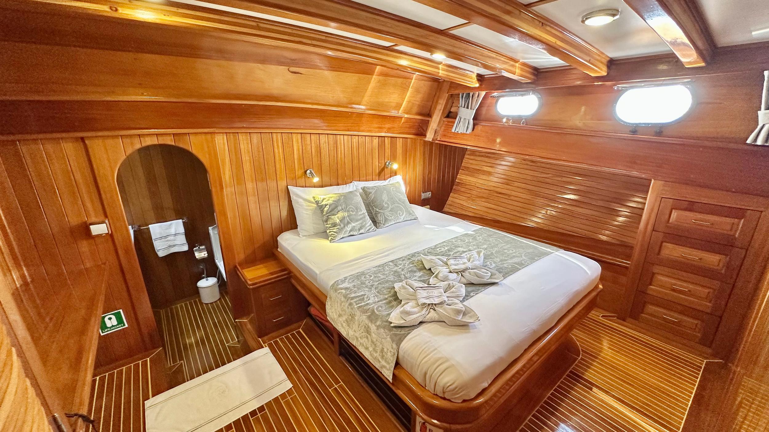 yacht guest cabin featuring double bed with patterned bedding and arched en-suite bathroom entrance