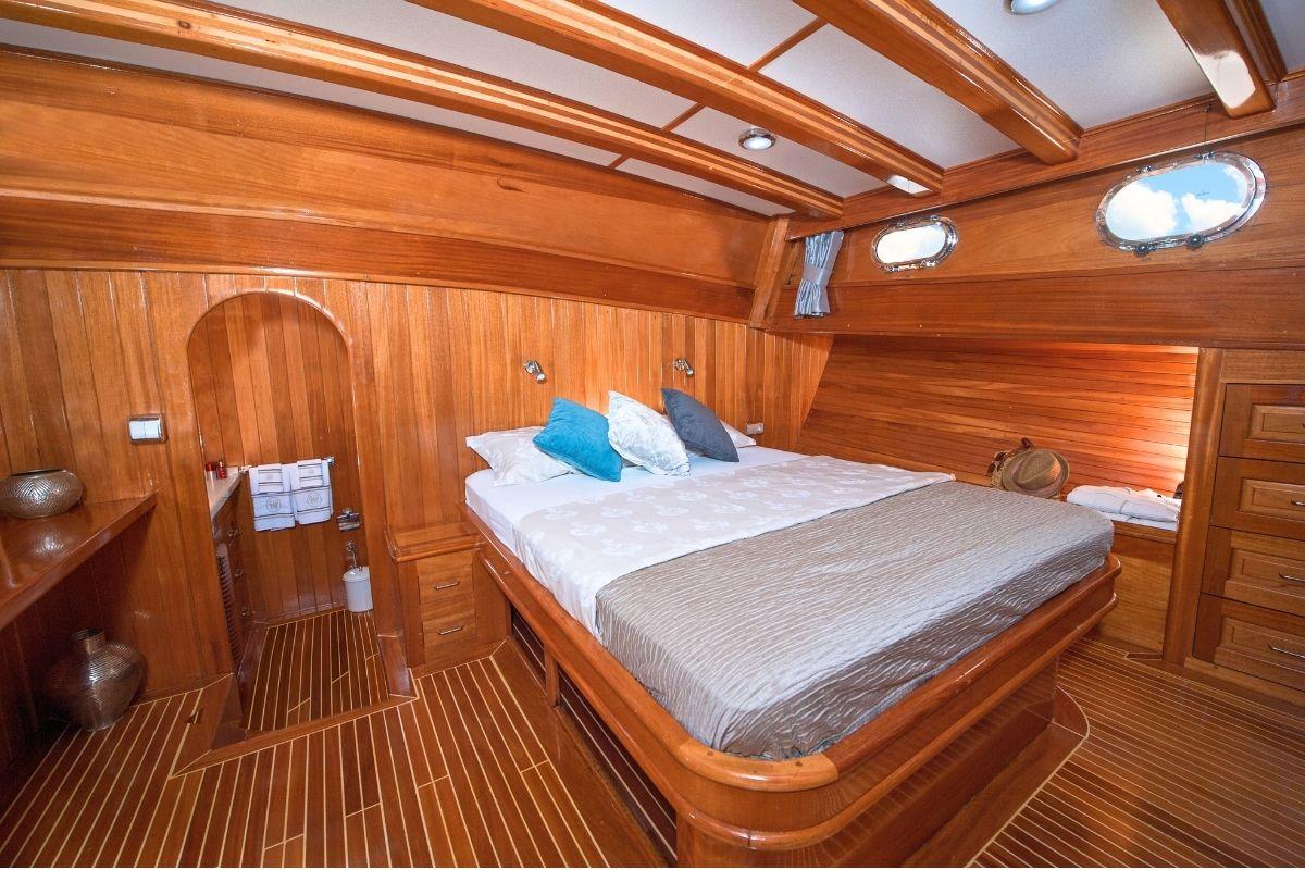 yacht cabin interior featuring double bed with decorative pillows and warm wood paneling