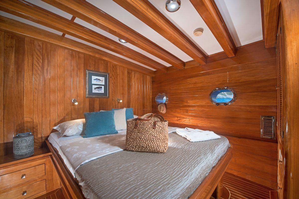 yacht guest cabin featuring double bed, wood paneled walls, nautical artwork and portholes