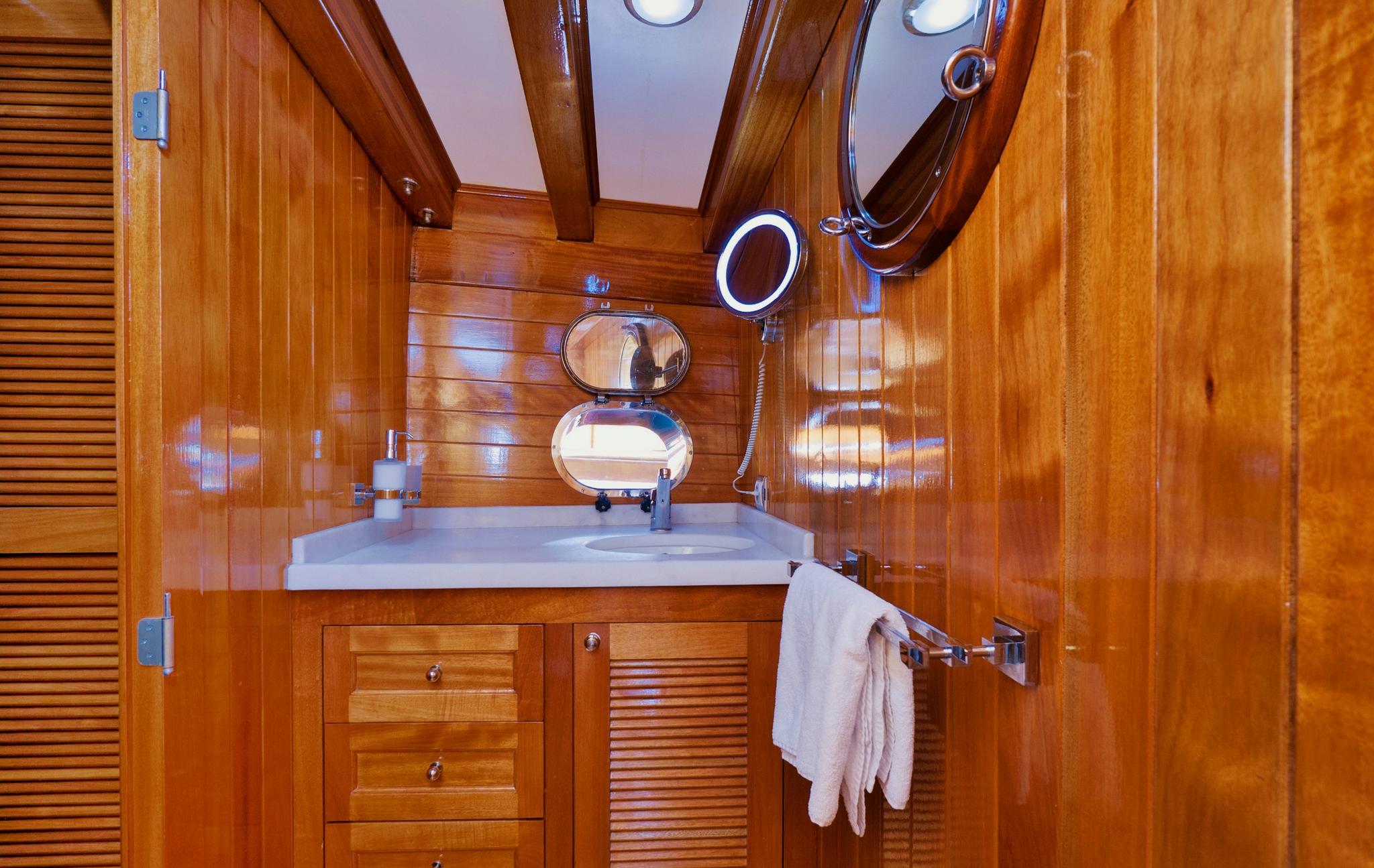 yacht bathroom featuring wooden vanity unit with white countertop and oval mirror
