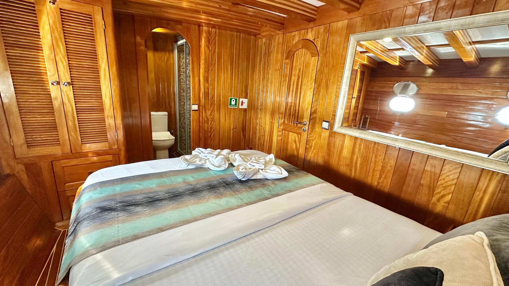 yacht guest cabin featuring double bed with decorative towels and en-suite bathroom with toilet