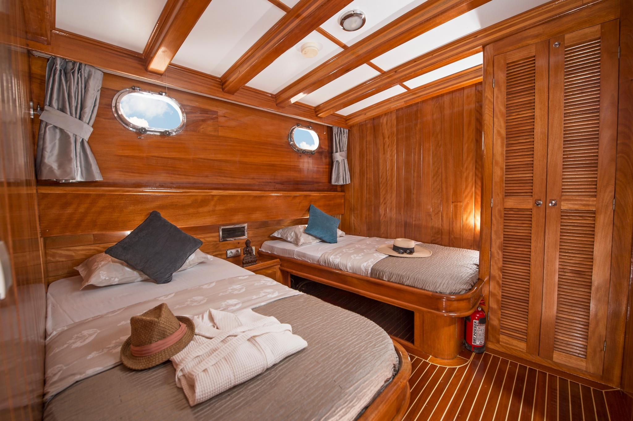 yacht twin cabin featuring two single beds with white linens and rich teak wood paneling