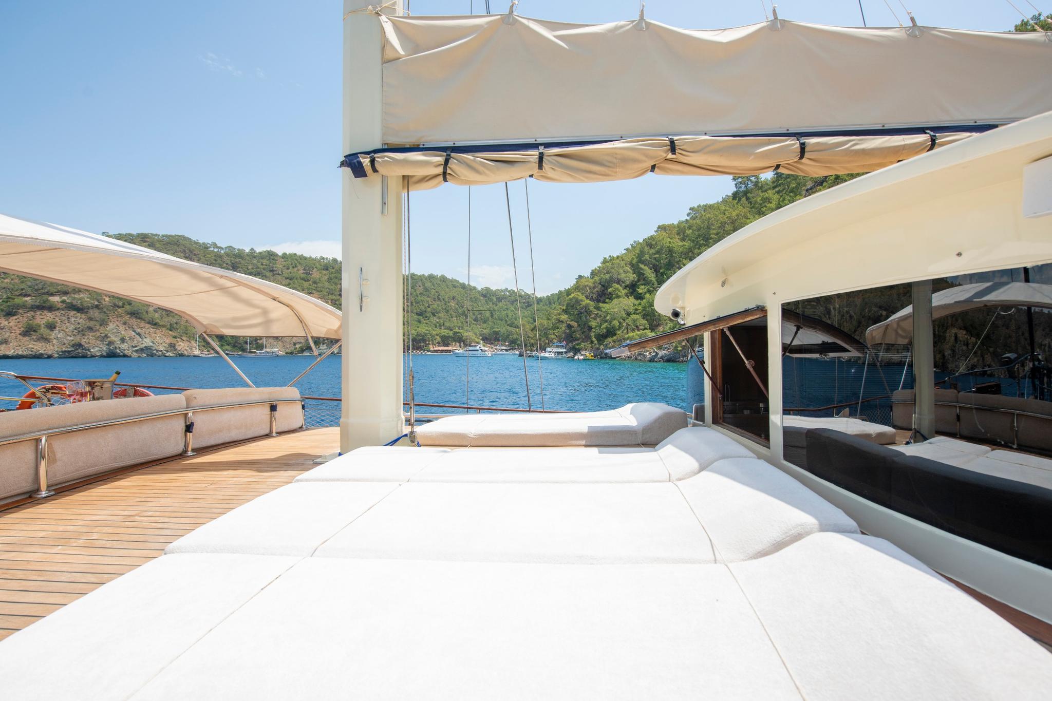 yacht aft deck with white cushioned seating area under beige fabric awning in Mediterranean bay