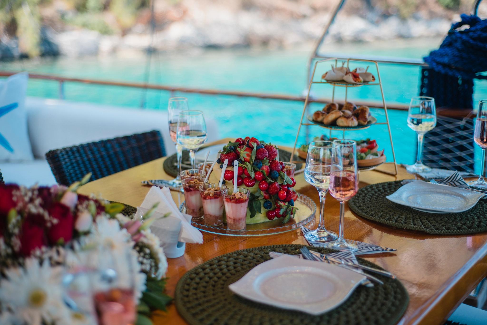 yacht dining table with tiered dessert stand, wine glasses and fruit presentation