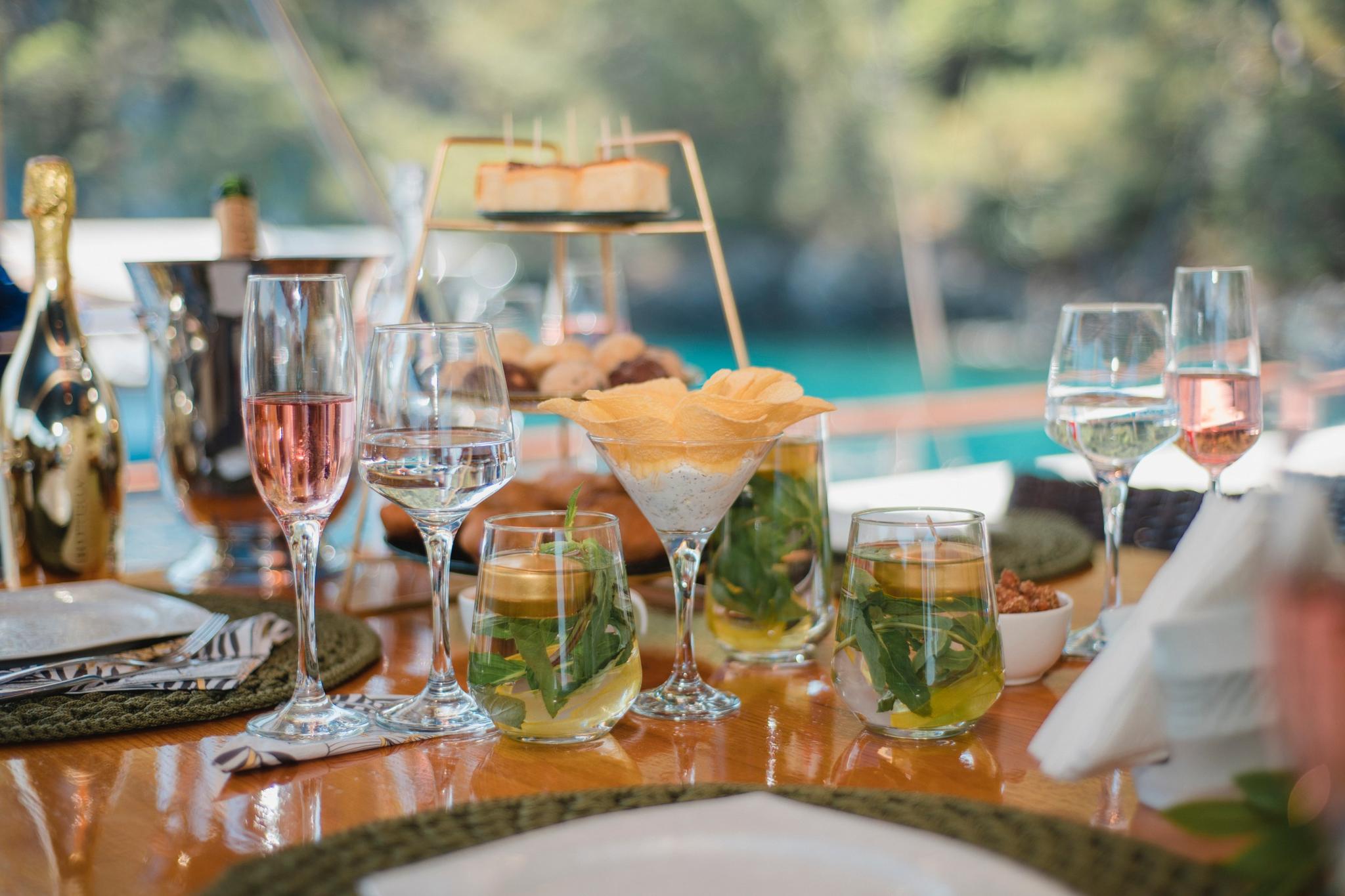 yacht dining table set with champagne flutes, cocktail glasses, and appetizers on polished wood surface