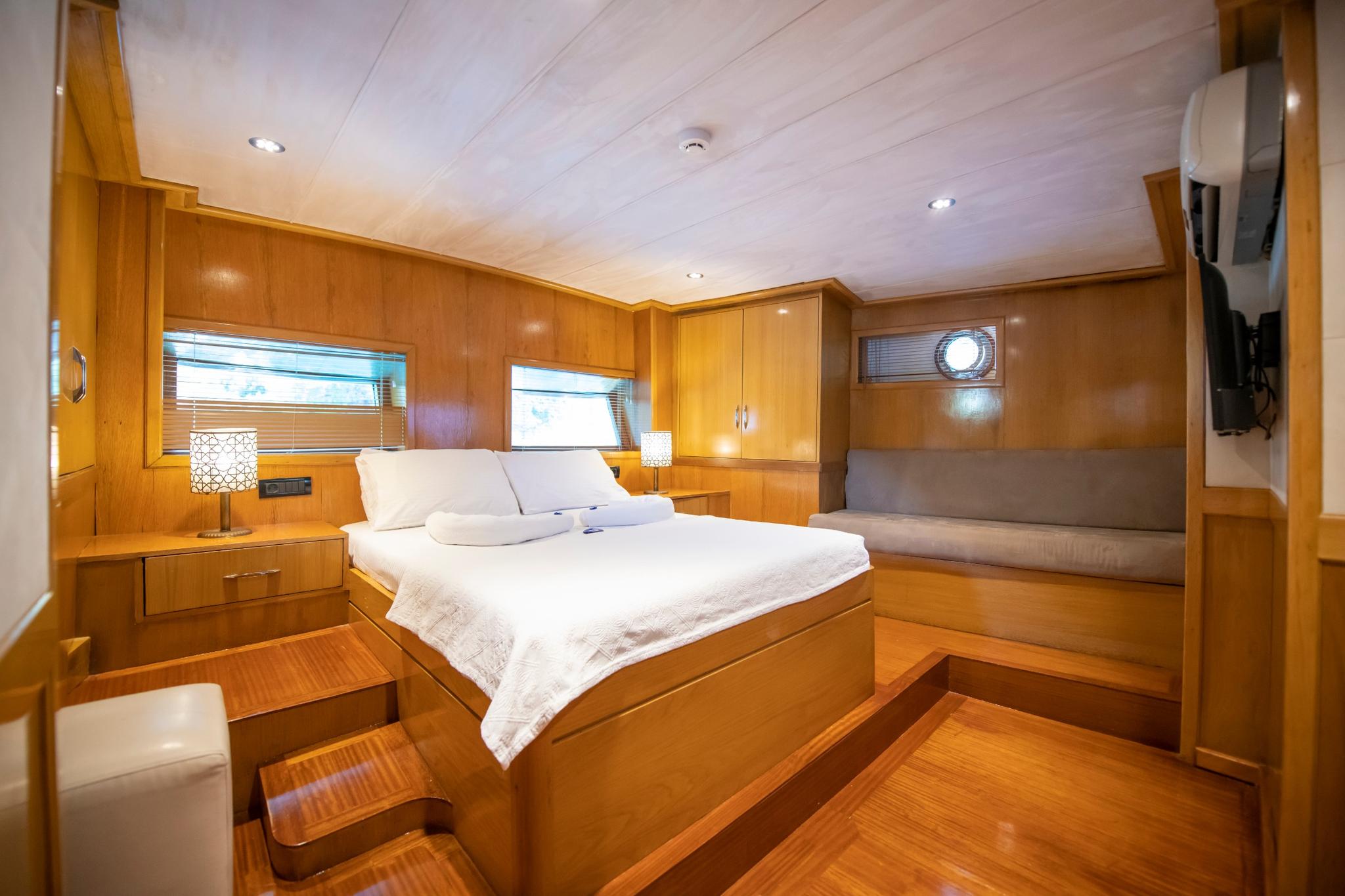 yacht cabin interior with double bed, wood paneling, built-in seating area and windows