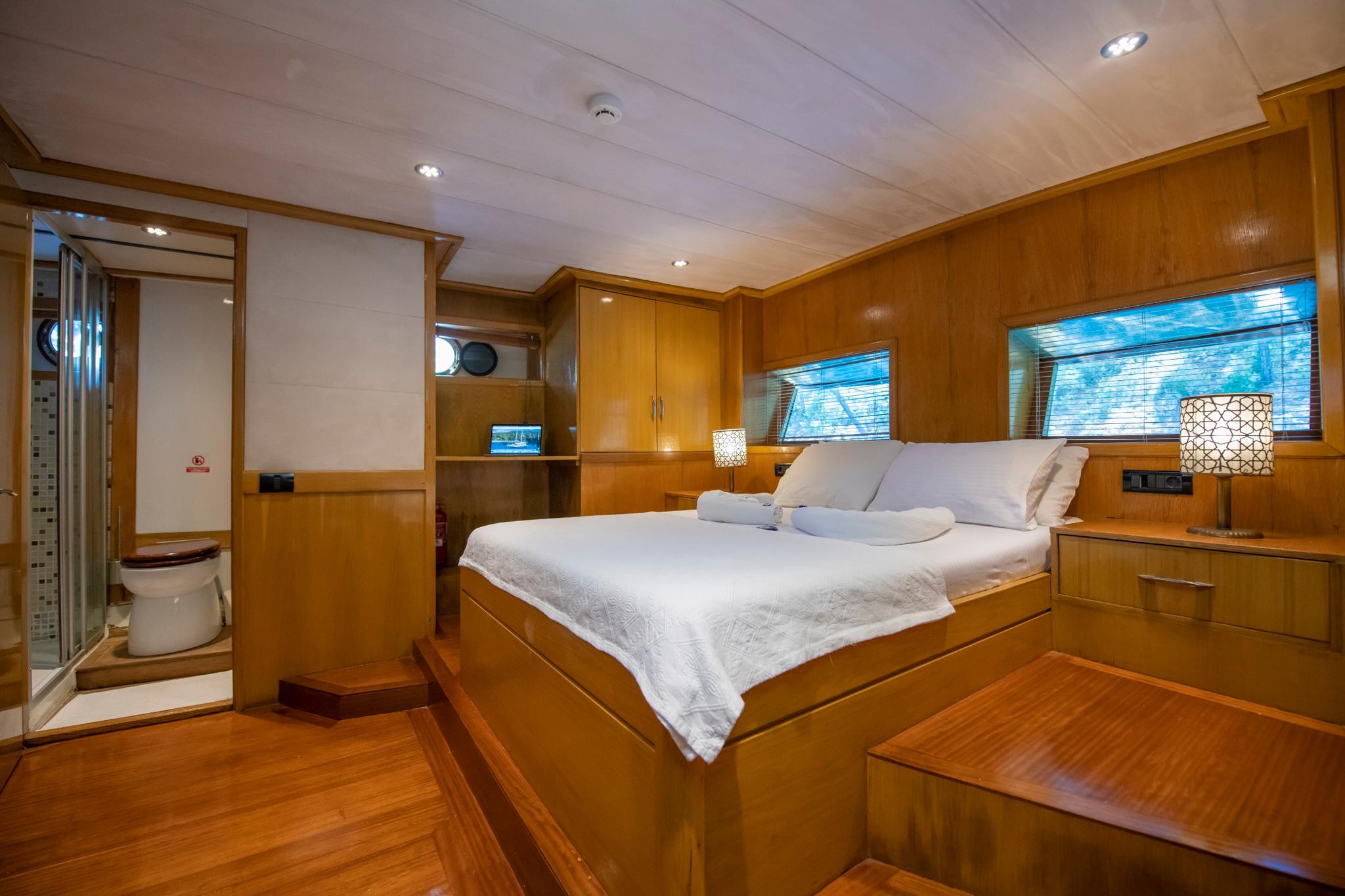 yacht cabin interior showing double bed with white linens and adjacent en-suite bathroom