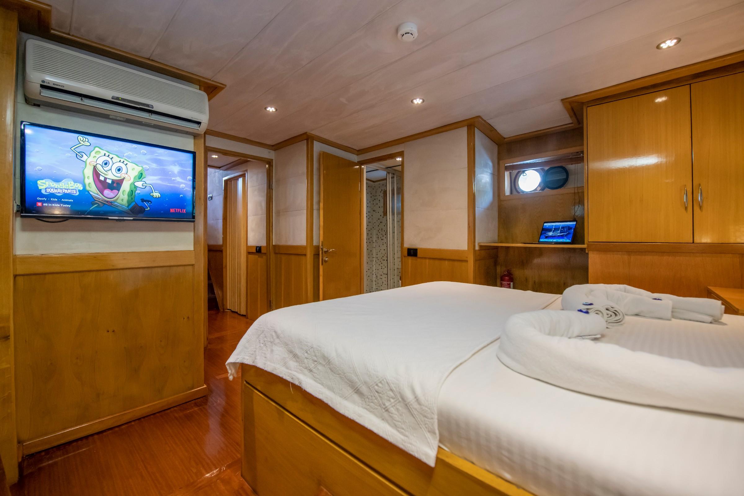 yacht guest cabin featuring double bed, wall-mounted TV, air conditioning and built-in storage