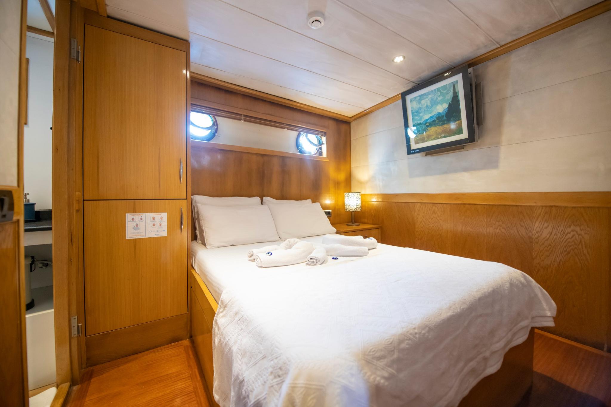yacht guest cabin featuring double bed with white linens and two round portholes