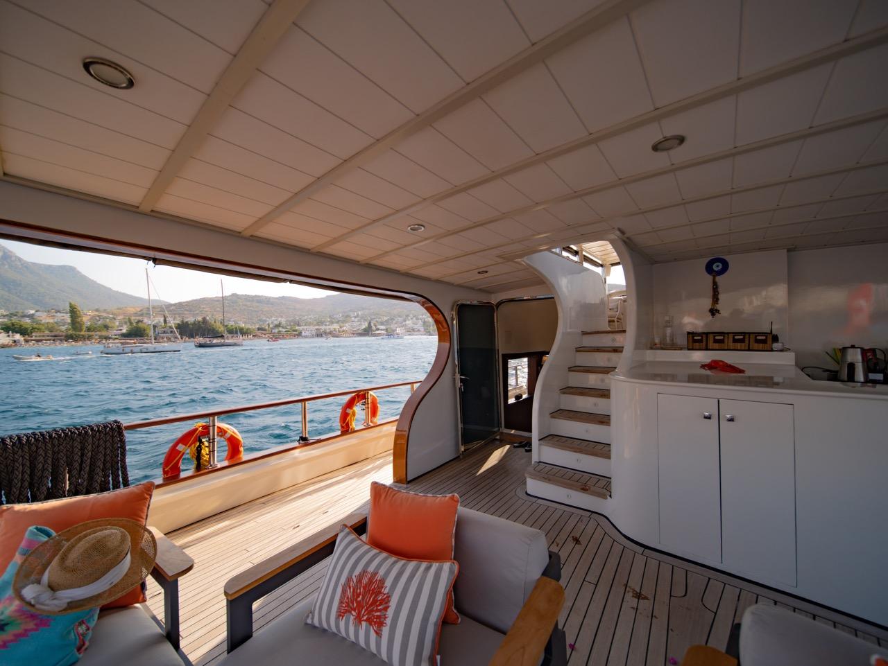 covered aft deck with built-in seating, stairs to upper deck, and galley area