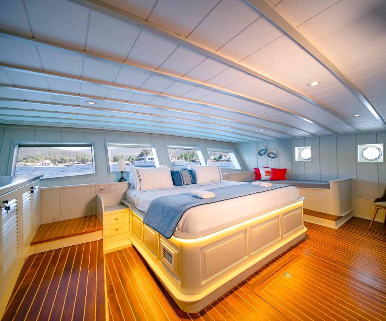 luxury yacht master cabin featuring king bed with blue bedding and panoramic side windows