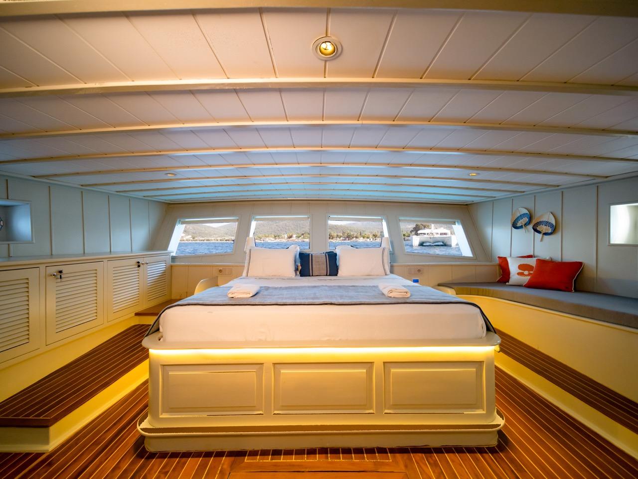 luxury yacht master cabin featuring king bed with panoramic windows overlooking water