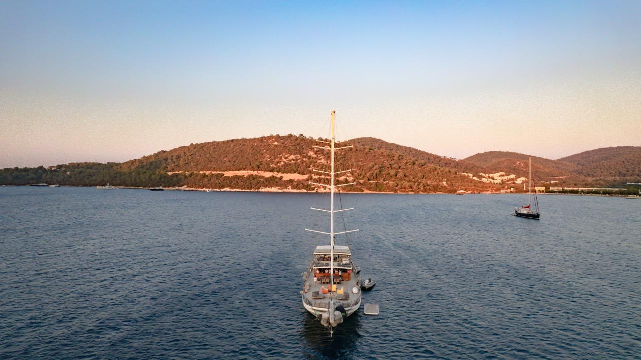 aerial view of white gulet yacht anchored in calm Mediterranean bay at sunset