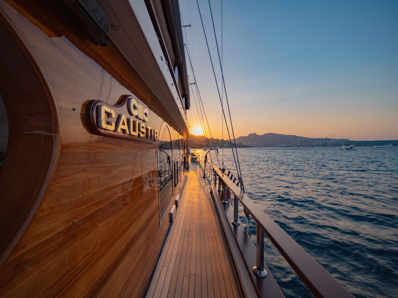 Gulet side deck with teak planking and yacht name at sunset