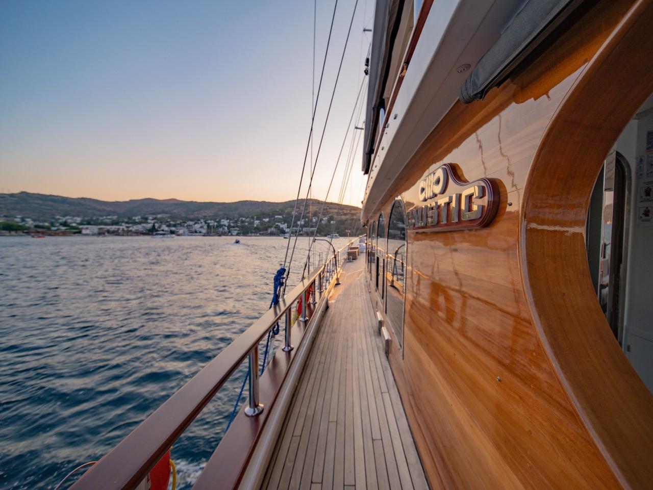 Gulet side deck with teak planking and stainless steel railings at golden hour