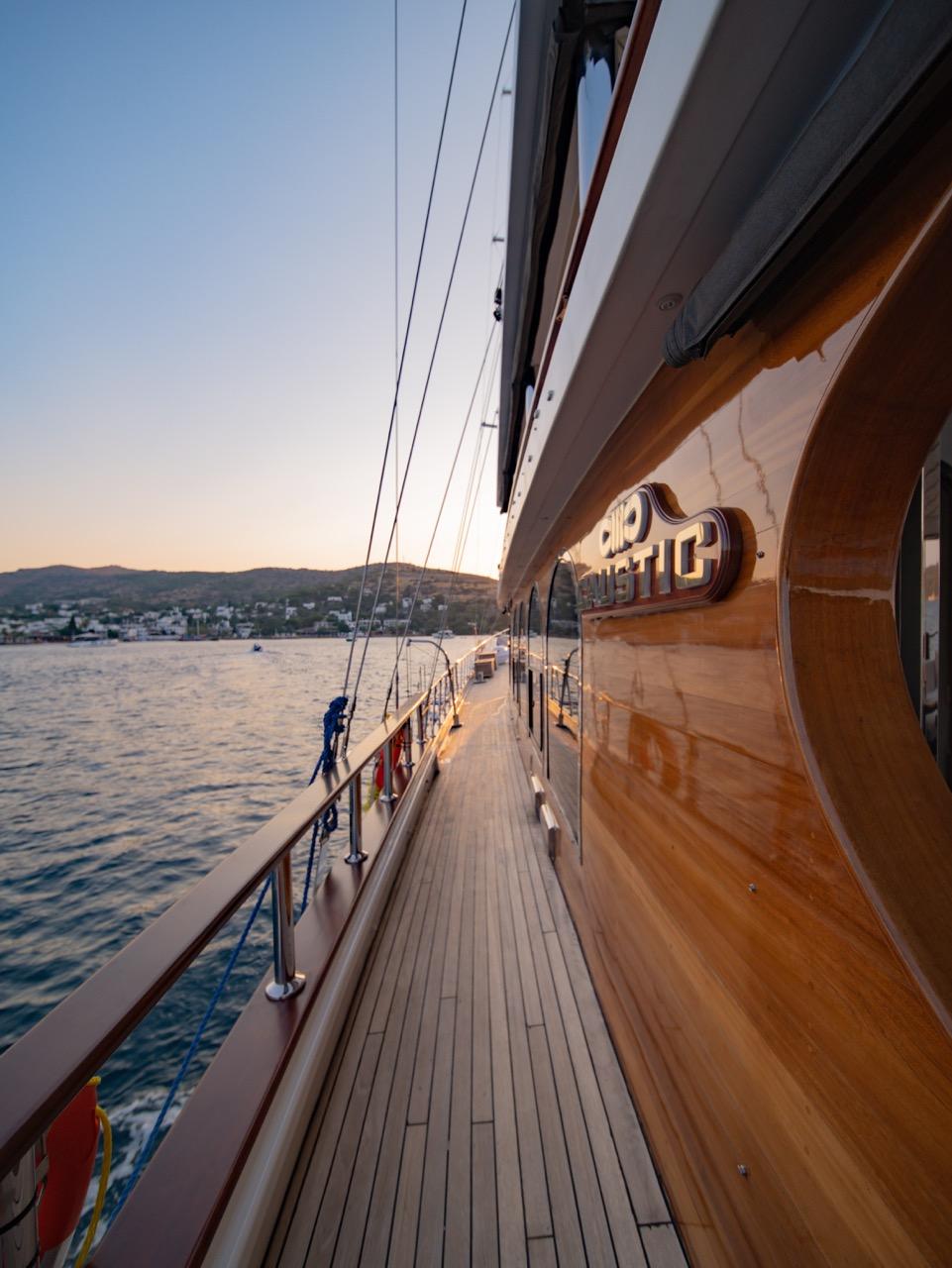 yacht side deck with teak planking and safety railings overlooking calm waters at sunset