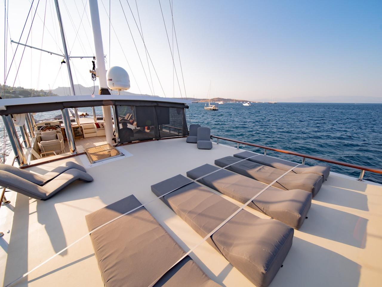Gulet foredeck sun lounging area with beige cushioned seating and white deck