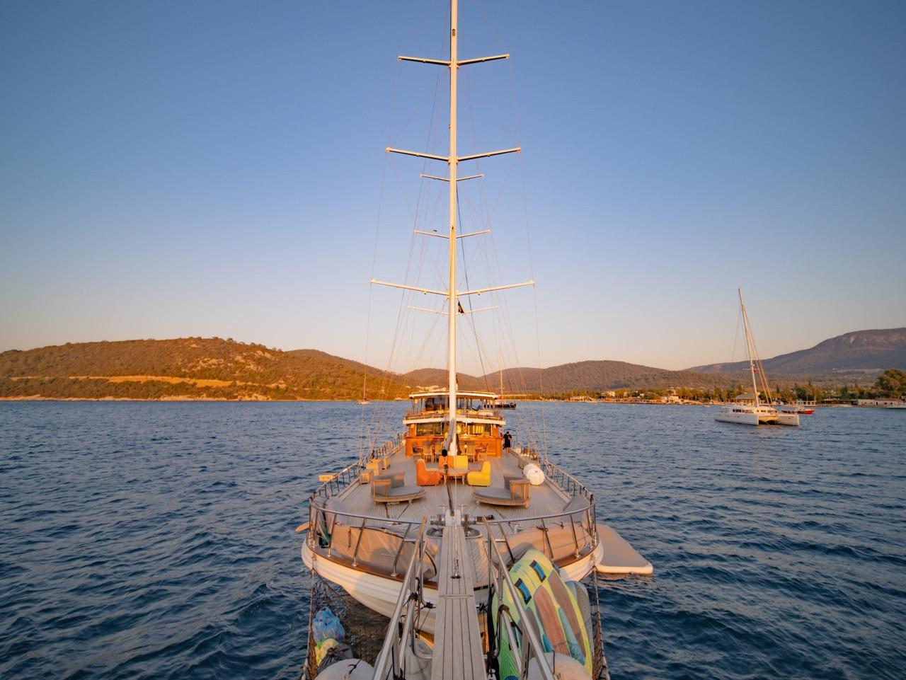 gulet stern deck with outdoor dining furniture and seating area at golden hour