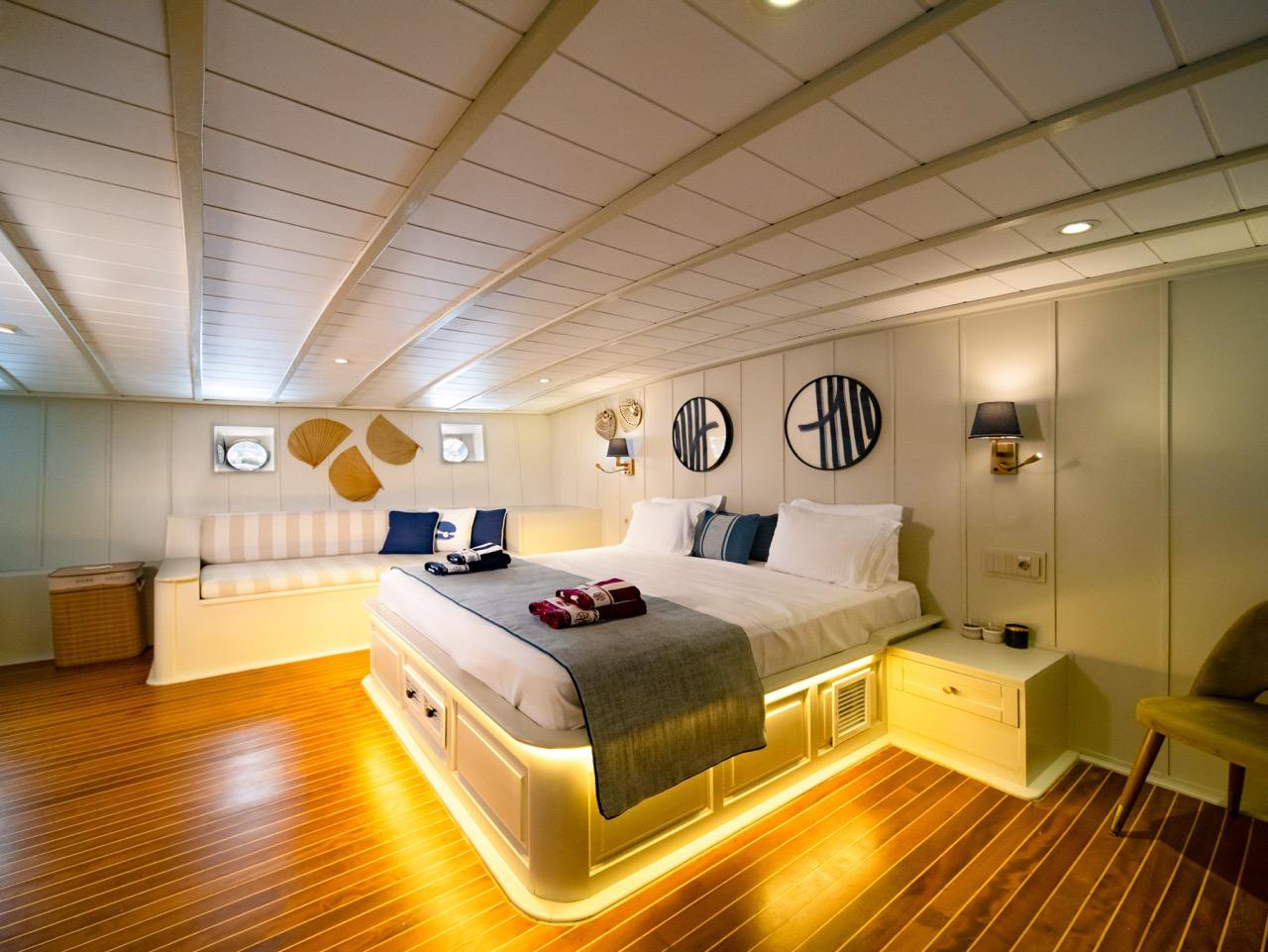 yacht guest cabin featuring double bed with ambient LED lighting and teak flooring