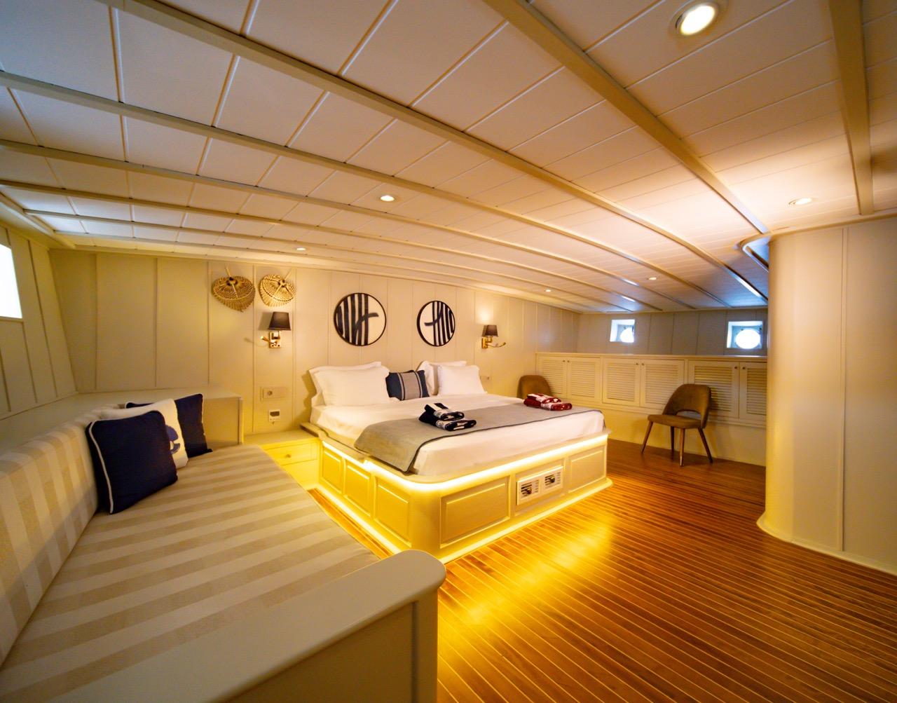 Luxurious master cabin featuring king bed with LED underlighting, built-in seating and portholes