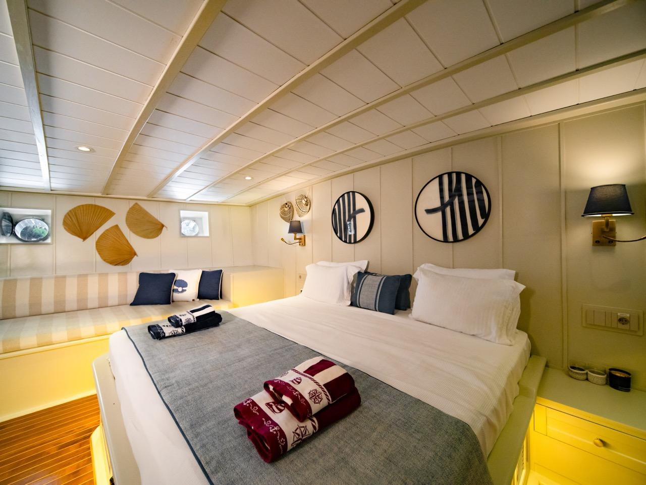 yacht guest cabin featuring twin beds with white linens, striped bench seating, and nautical wall decor