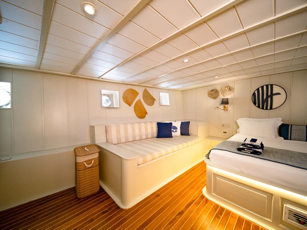 yacht cabin interior with white built-in seating, sleeping berth, and orange accent lighting