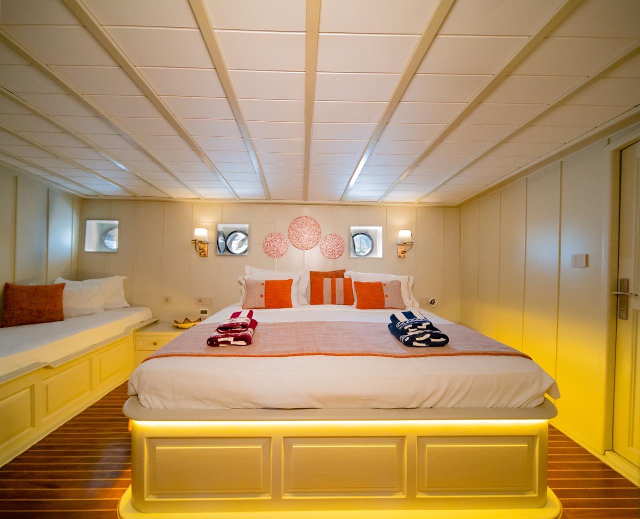 yacht guest cabin featuring double bed with orange pillows and built-in seating area
