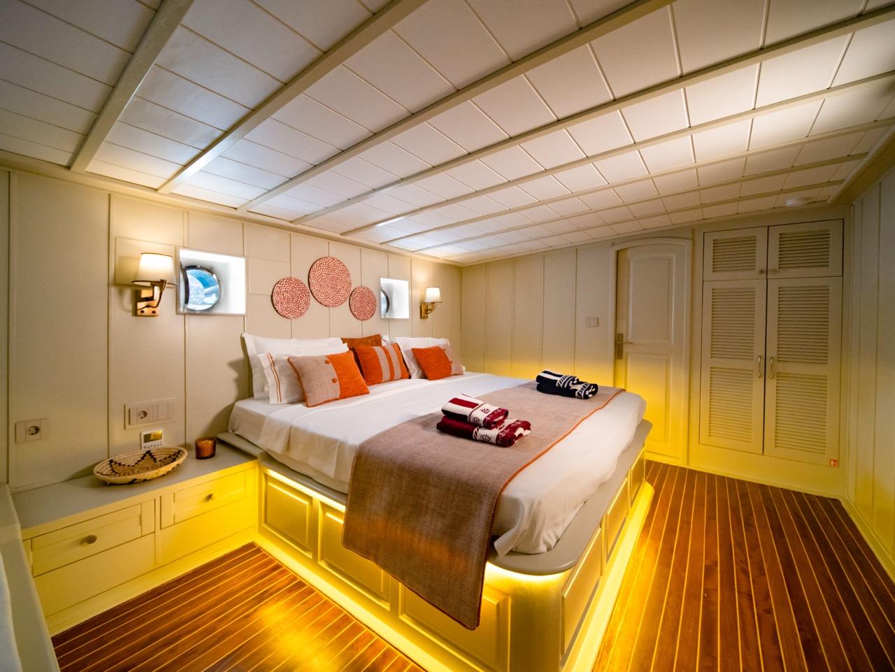 yacht guest cabin featuring double bed with orange accent pillows and ambient LED lighting