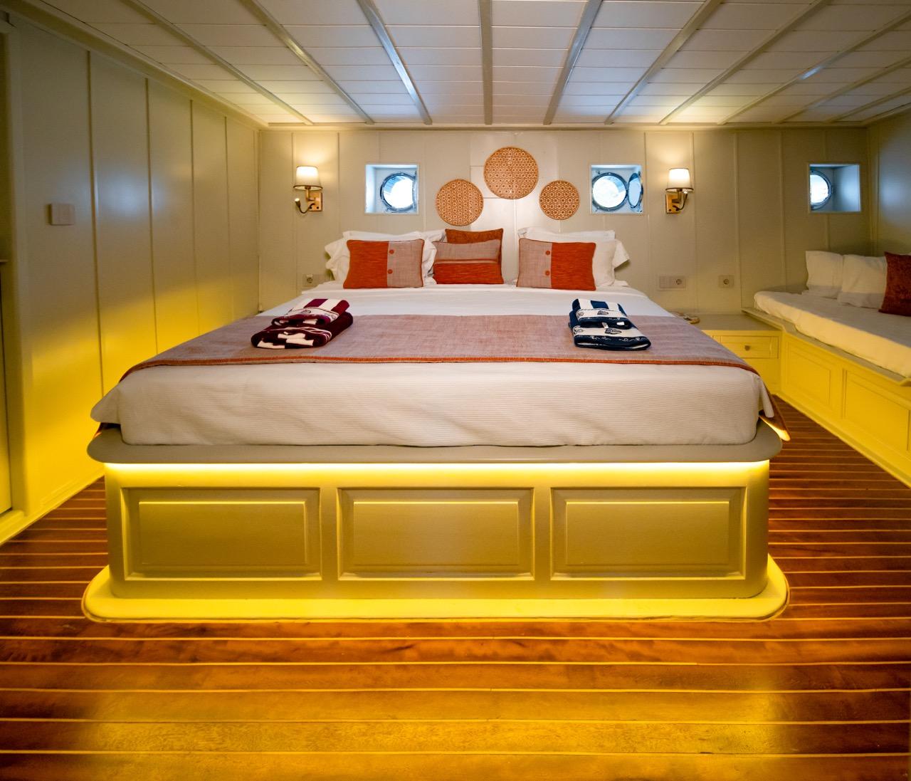 yacht master cabin with king bed, orange accent pillows, circular wall decorations and portholes