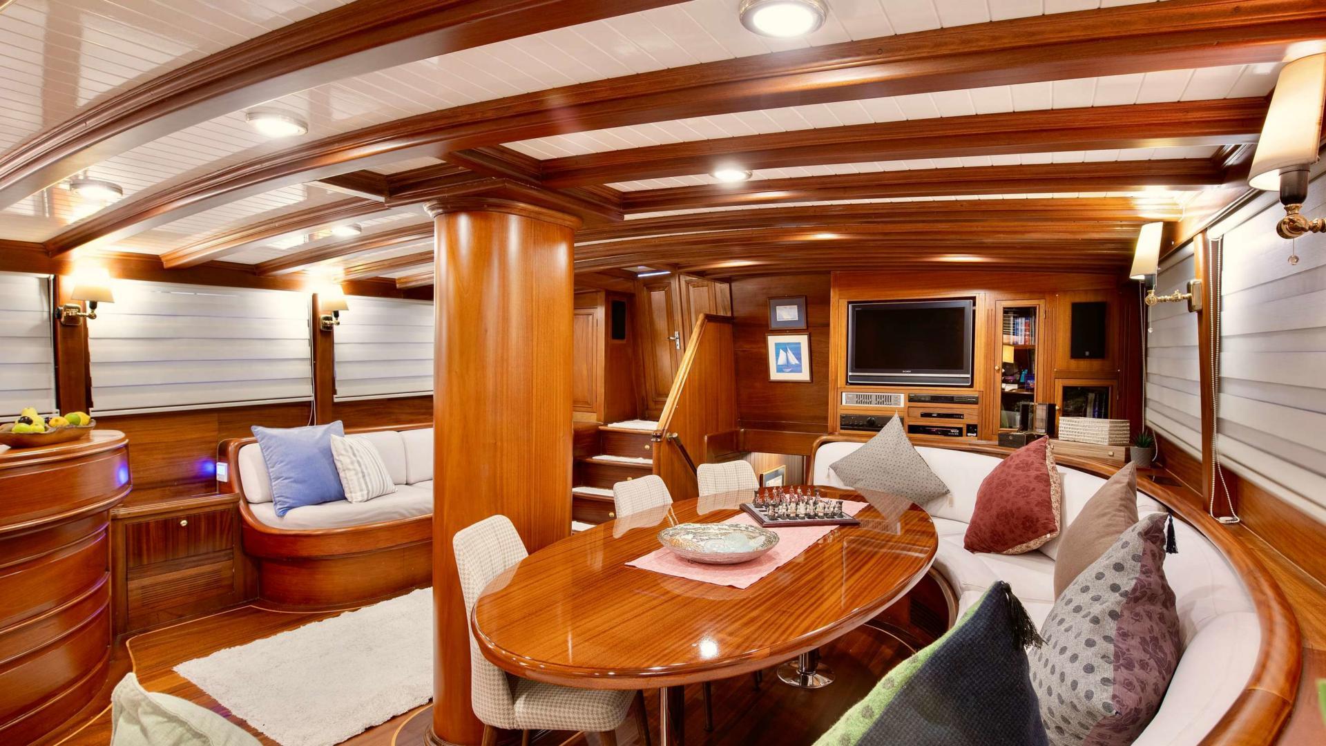 yacht interior salon with curved dining banquette, oval table, and entertainment center