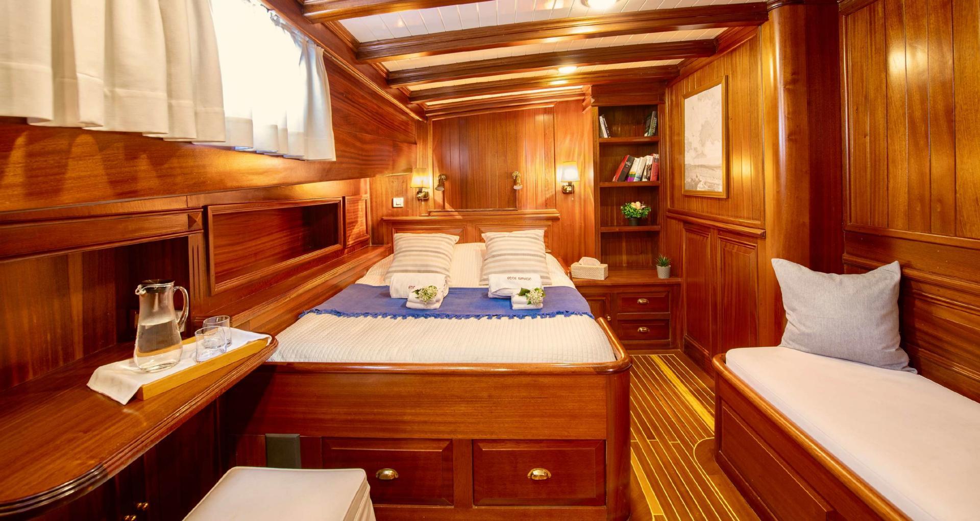 yacht guest cabin featuring double bed, rich wood paneling, built-in storage and seating area