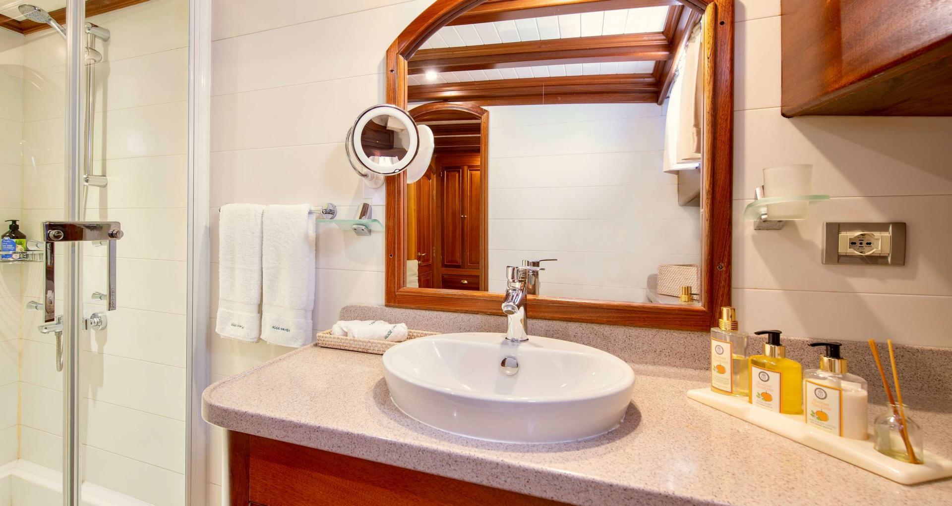 yacht bathroom featuring white oval vessel sink on granite countertop with wooden-framed mirror