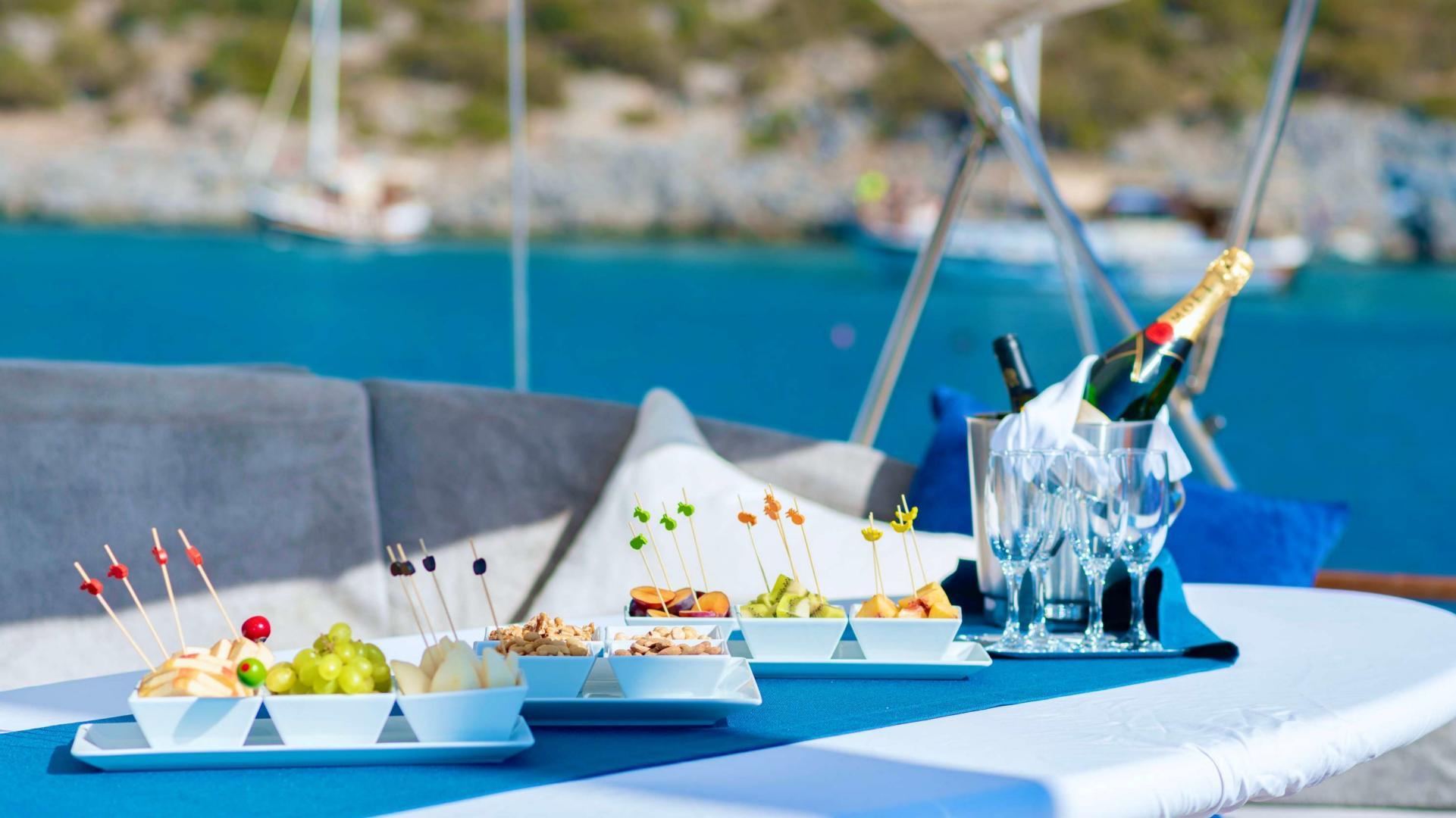 elegant canapés on white serving dishes with champagne glasses and ice bucket on yacht deck table