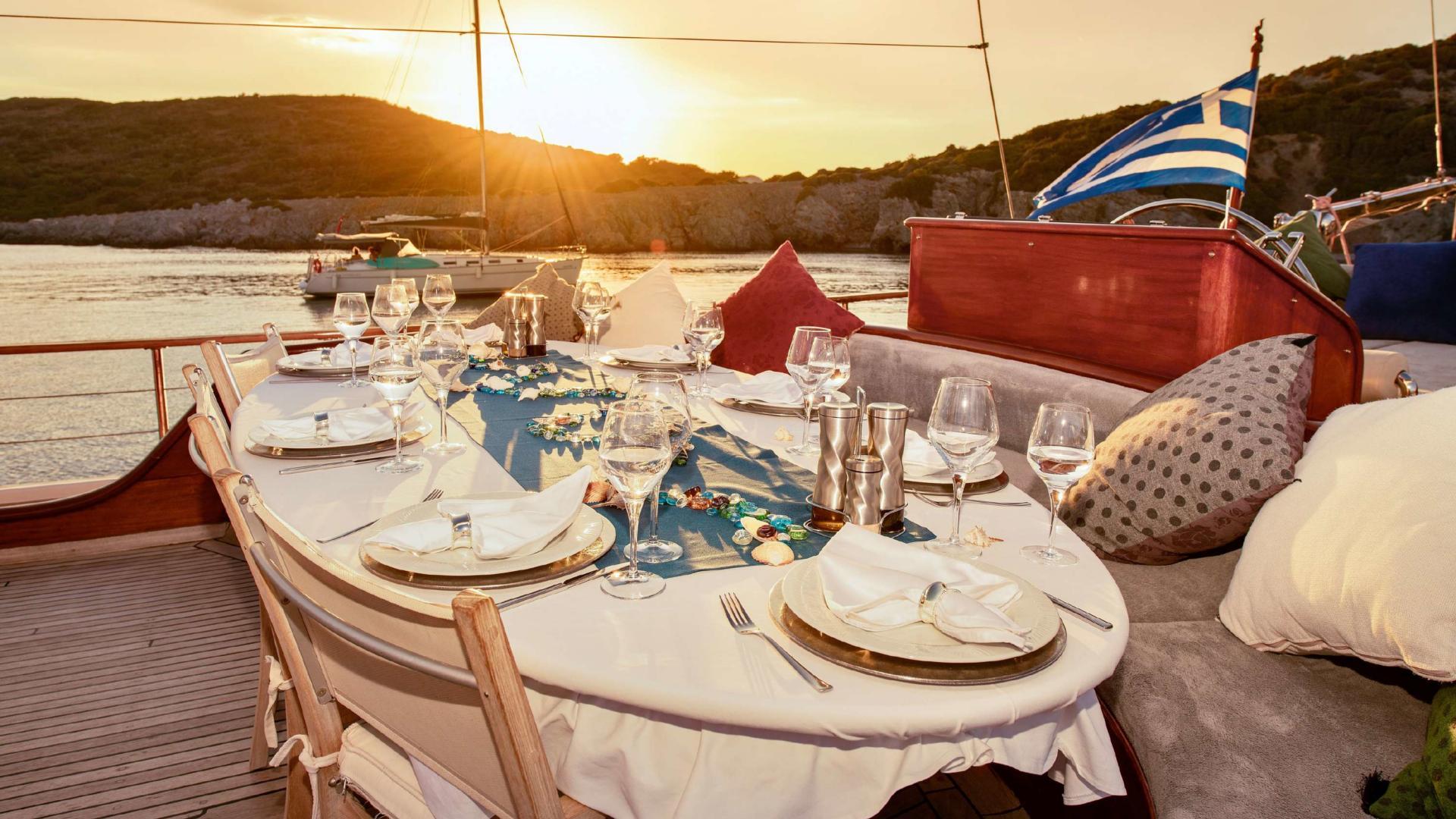 Elegant yacht dining table set with plates, glasses and table runner at golden hour