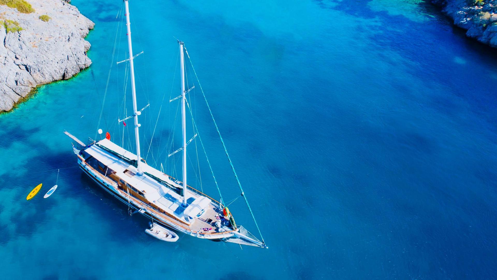 aerial view of traditional wooden gulet yacht anchored in crystal clear turquoise Mediterranean bay