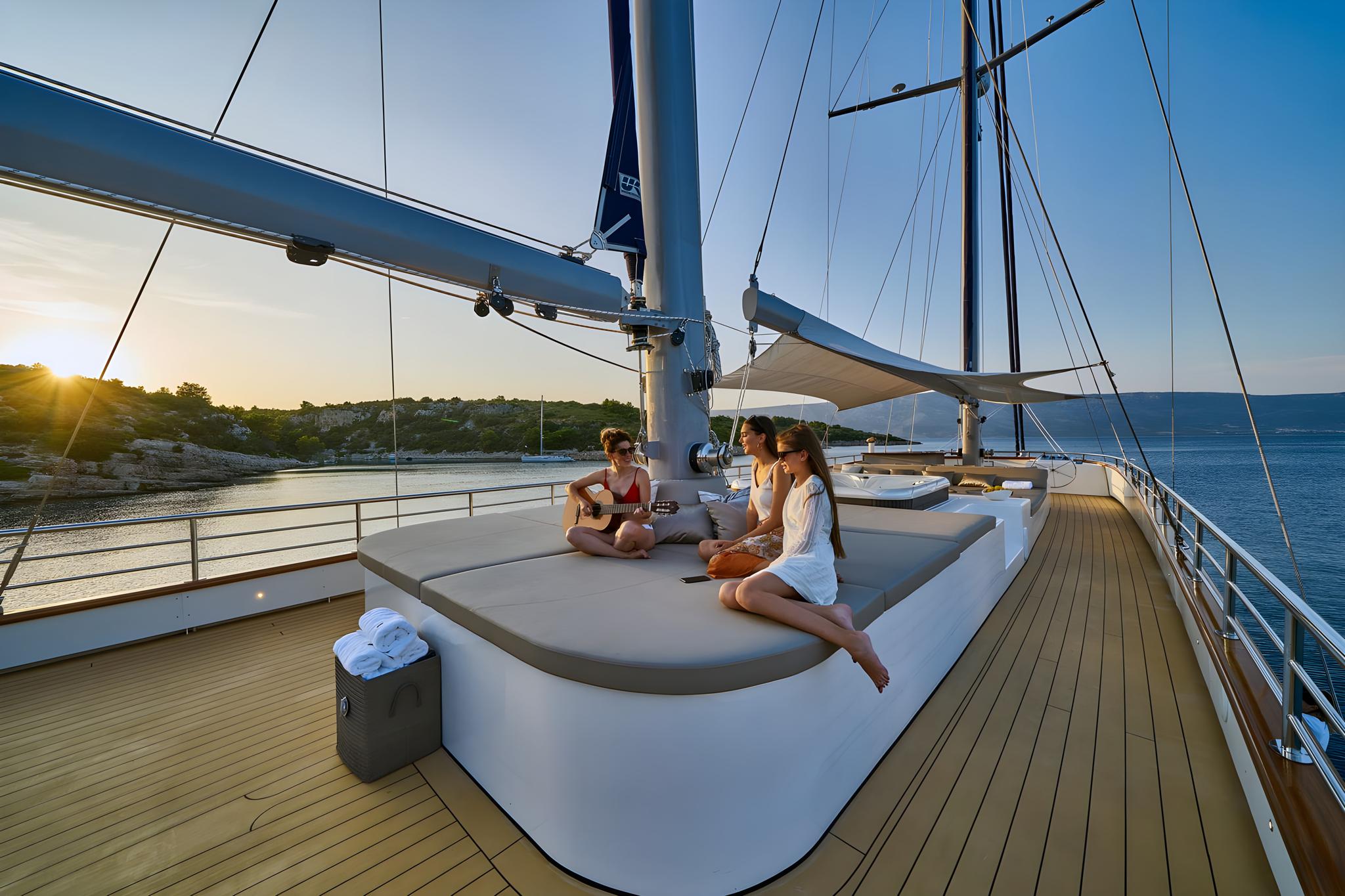 luxury yacht foredeck with guests on white sunpad during golden hour
