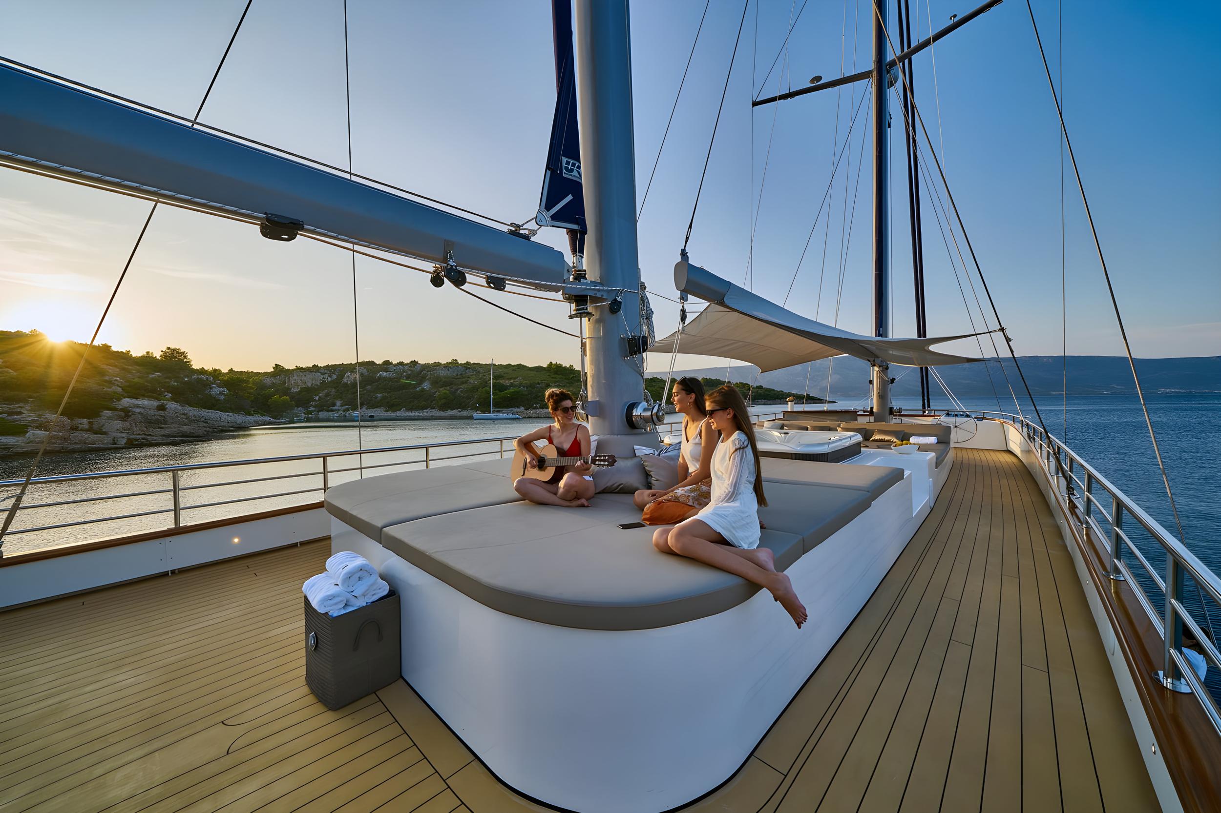 luxury yacht foredeck with guests on white sunpad during golden hour