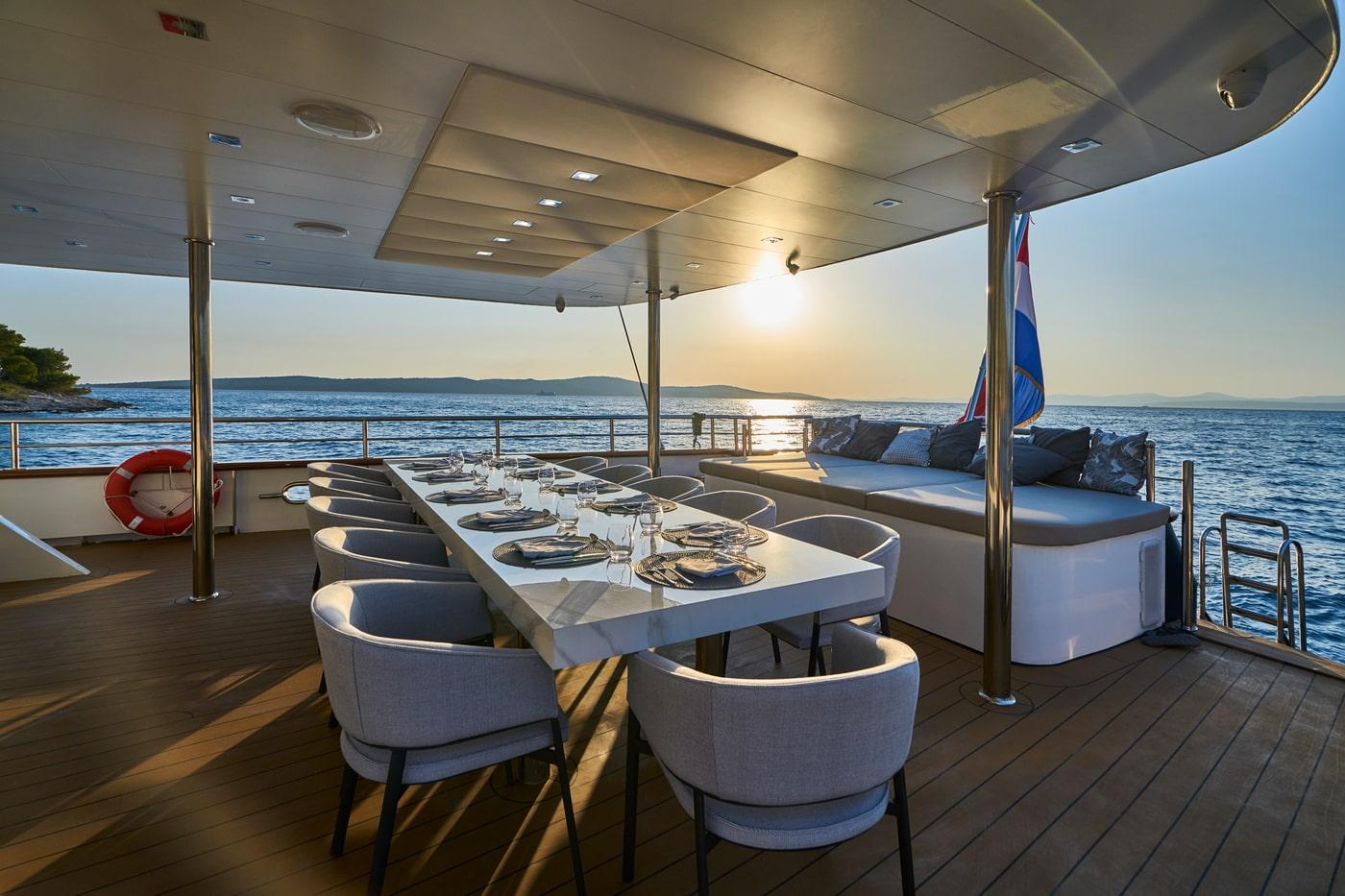 luxury yacht aft deck dining area with white table set for eight guests