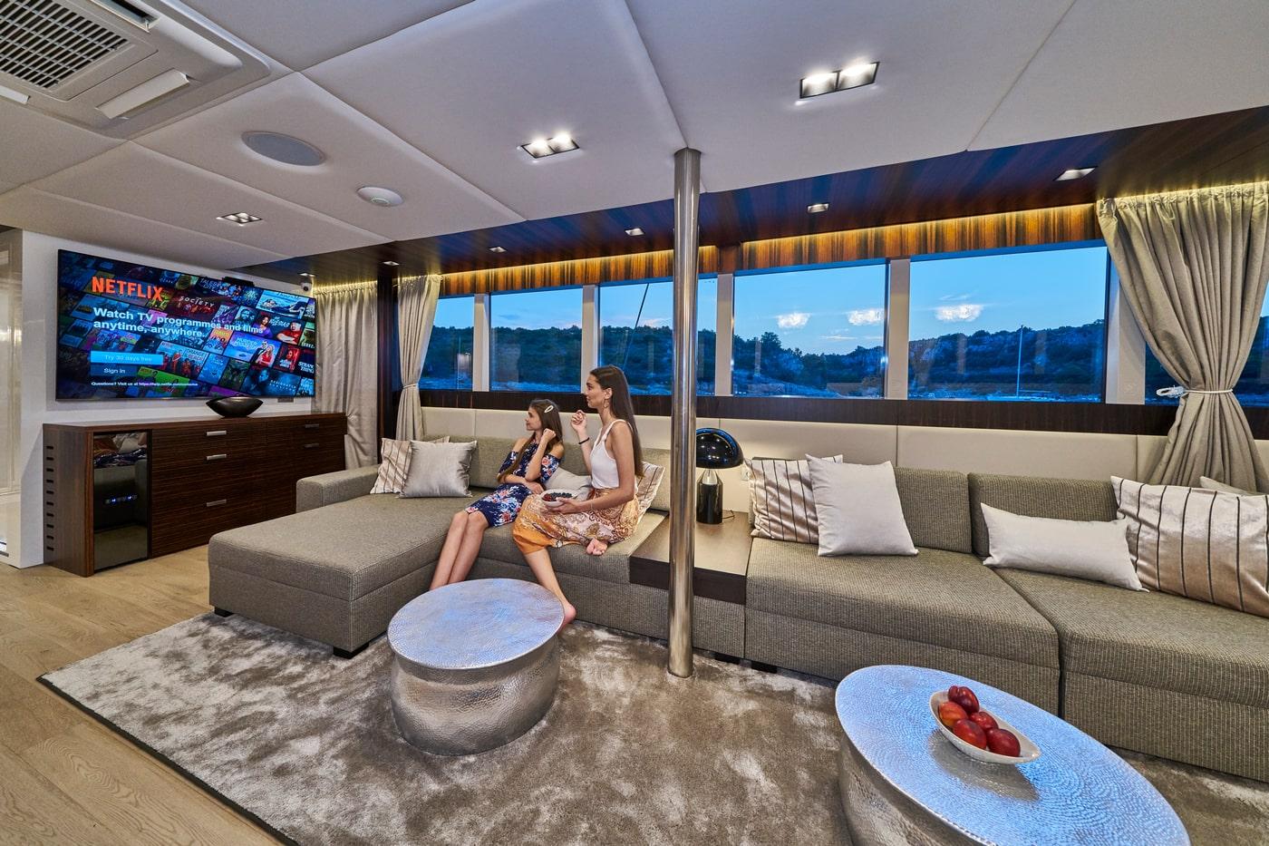 Modern yacht salon interior with gray seating and panoramic coastal views