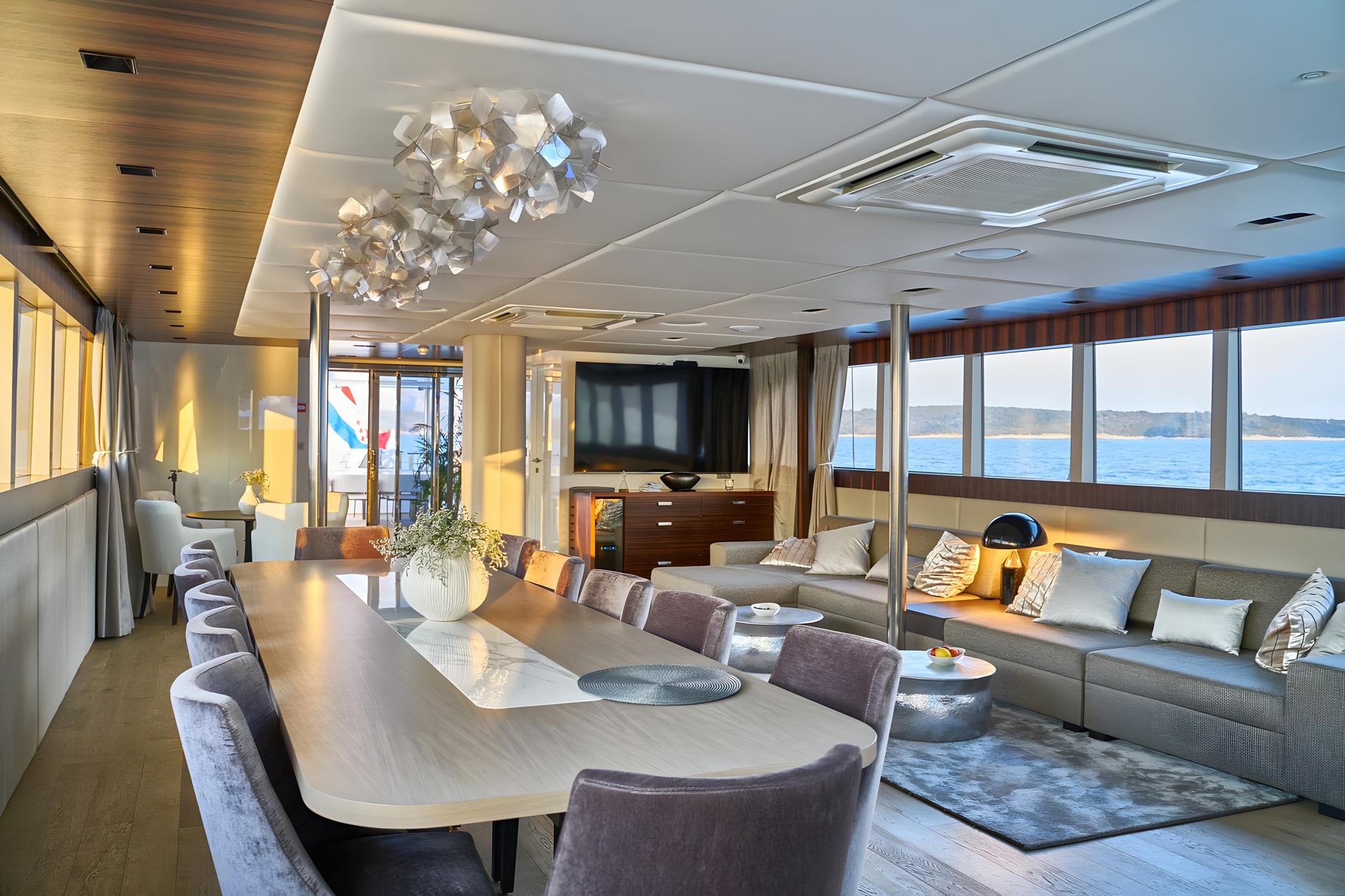 Modern yacht salon interior with dining table, sectional sofa and panoramic windows