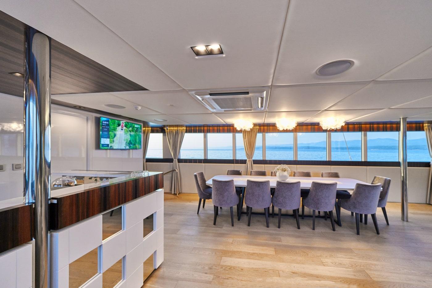 luxury yacht main salon with dining table and galley area