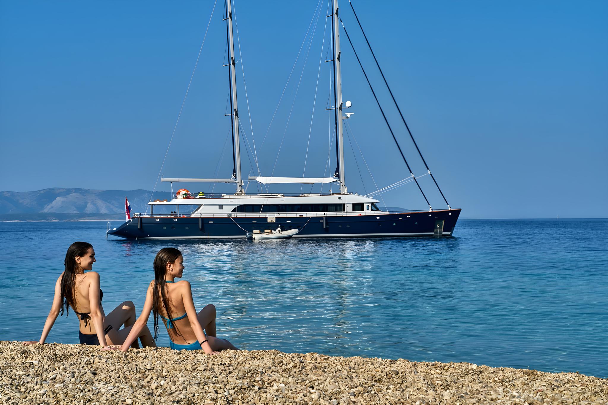 Dark blue luxury sailing yacht anchored in crystal clear Mediterranean waters